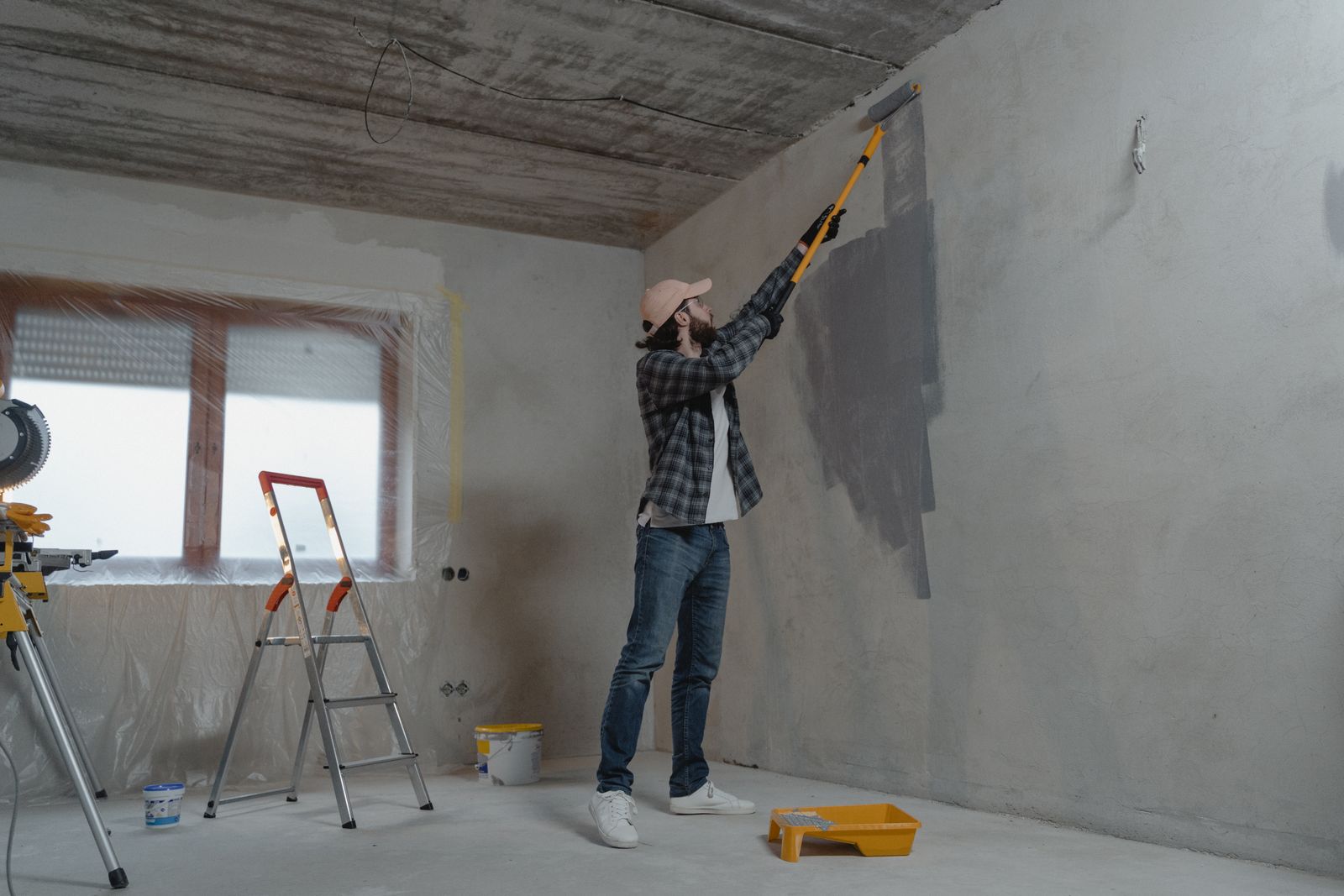 A decorator rolling a first coat onto a newly prepped wall