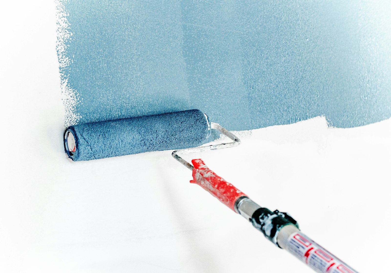 A paint roller laying a clean coat of blue-grey paint