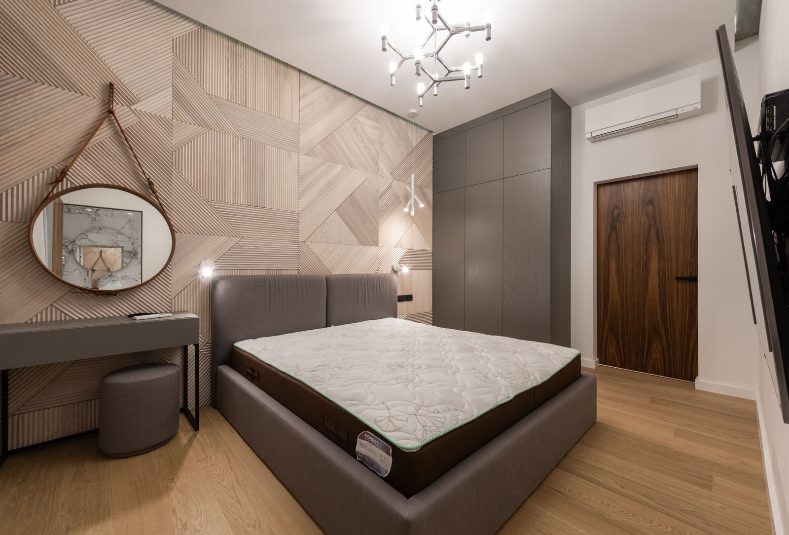 A bedroom with a geometric feature wall and clean painted woodwork